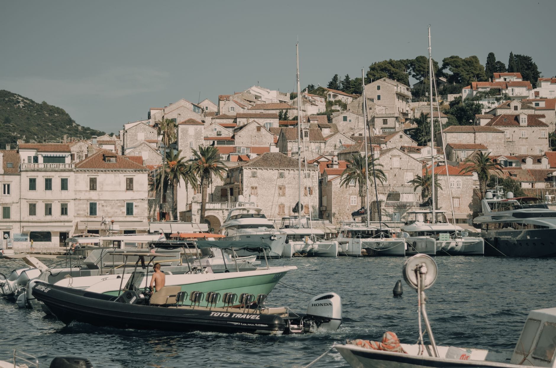 Boats in Hvar Town harbour beneath its stone hillside houses
