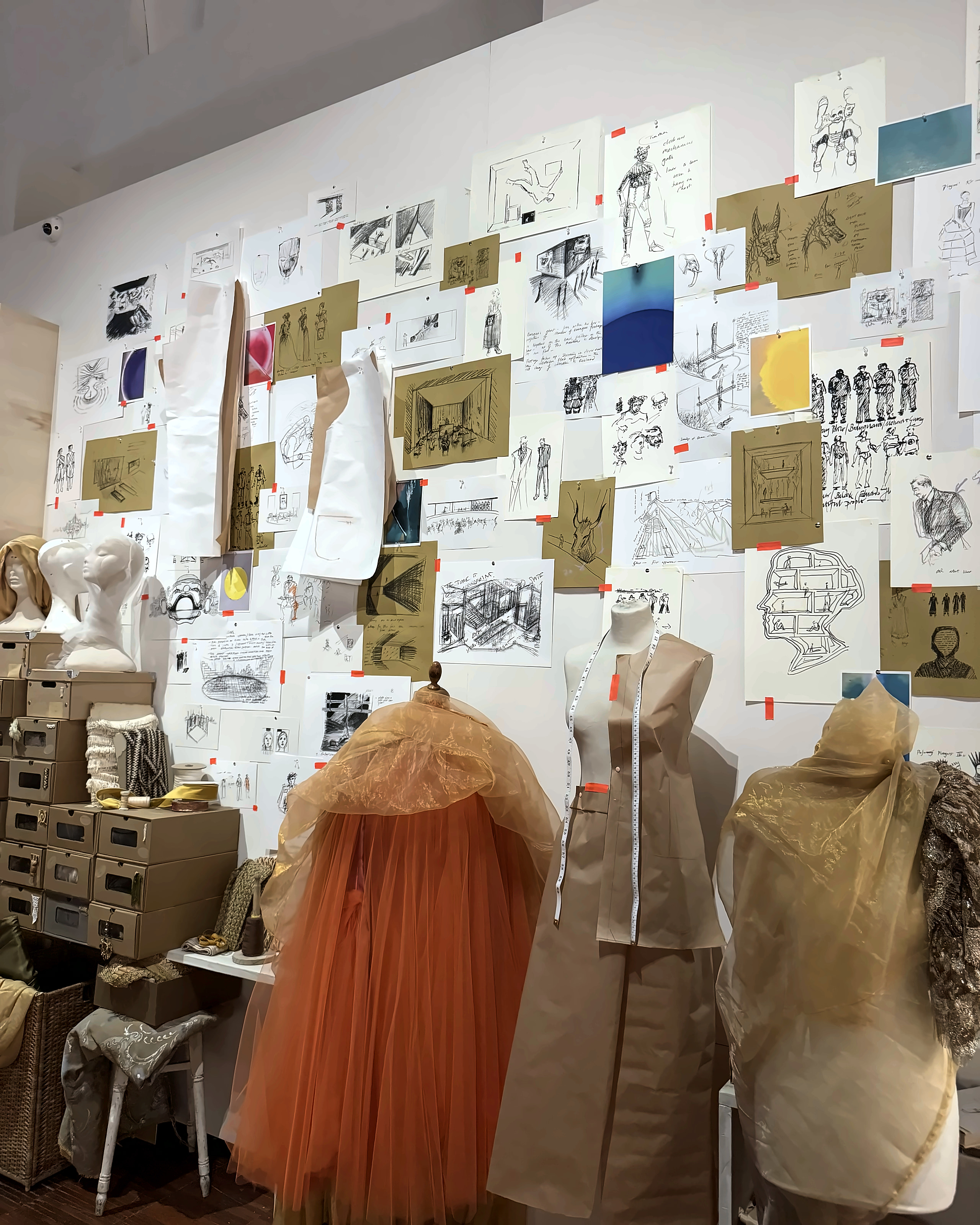 Fashion sketches pinned above dress forms in a couture studio