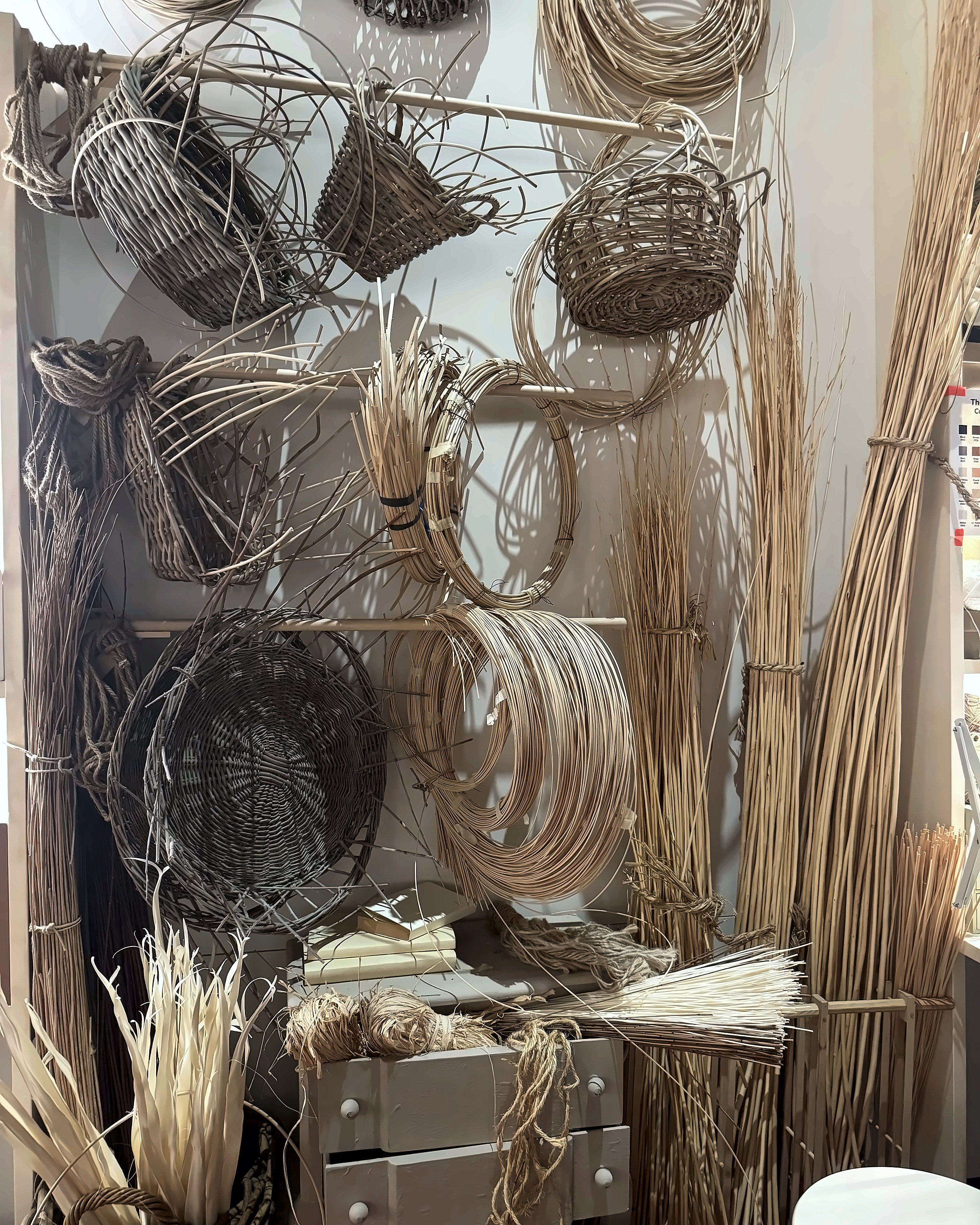 Hanks of willow and cane hanging above half-made baskets