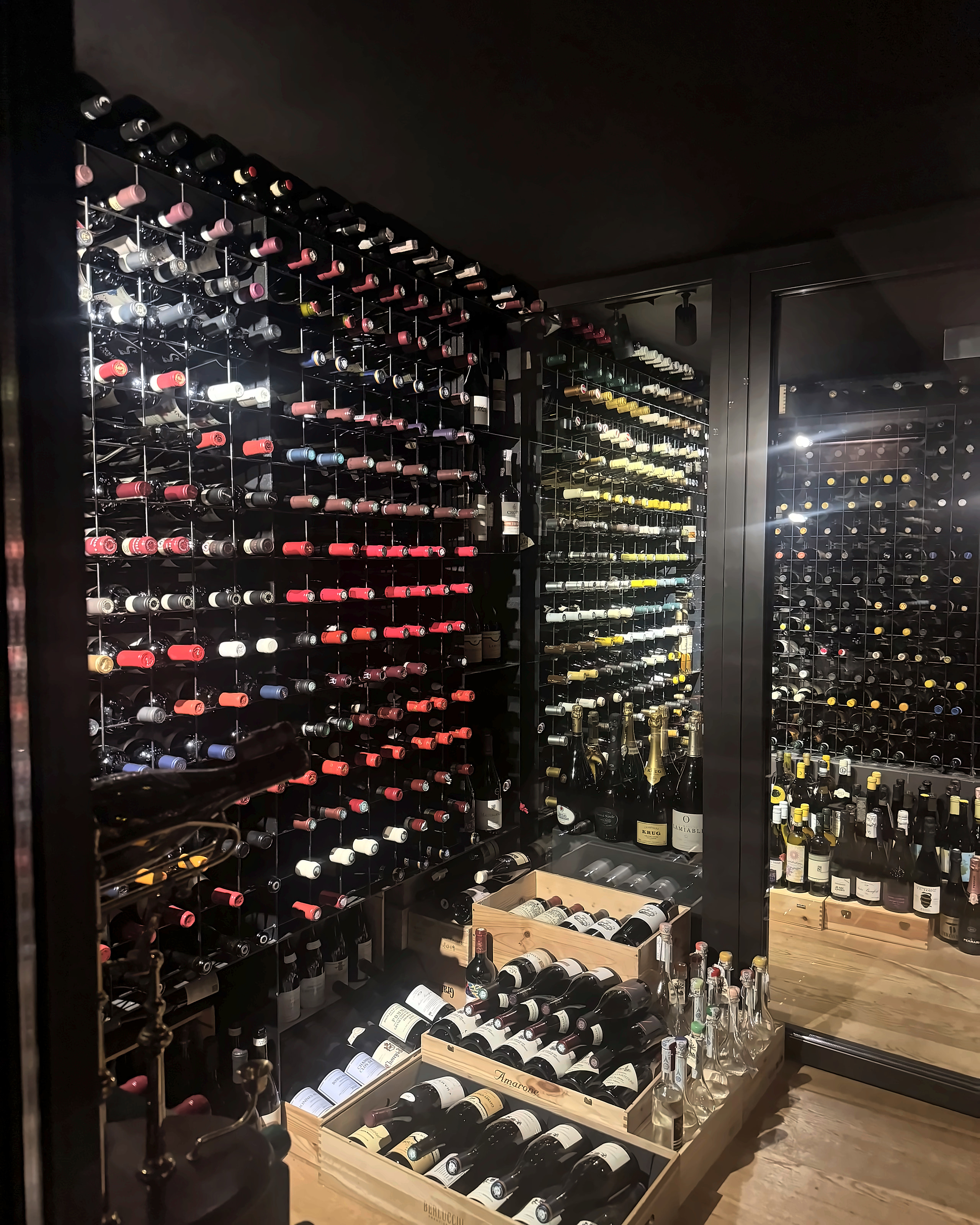 A tall lit wall of wine bottles at Gran Caffè Quadri